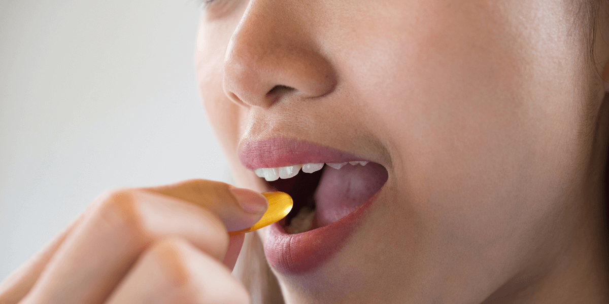 Girl holding a tablet near her mouth, ready to take the medicine.