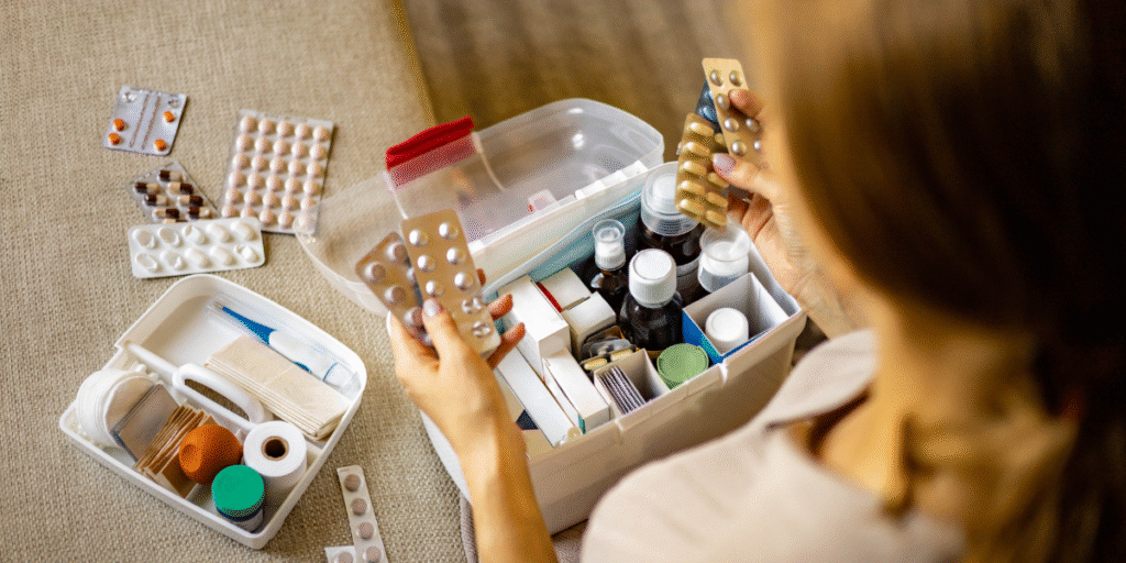 A woman standing over a medicine box at home, checking and organizing medications.