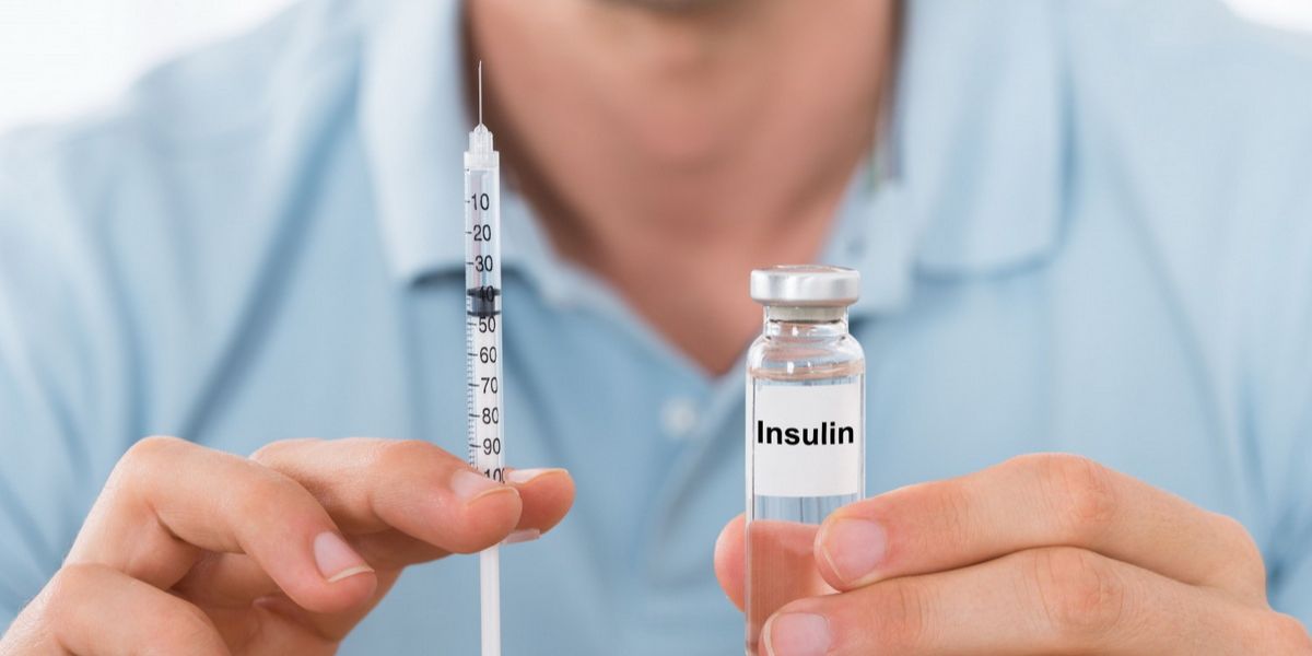 Man holding a syringe and a vial labeled "Insulin," illustrating diabetes management with insulin therapy